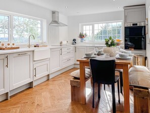 A modern kitchen with white cabinetry, a wooden dining table, and a built-in oven. - 2 bedroom accommodation in Clitheroe and the Ribble Valley (Clitheroe and the Ribble Valley)