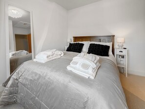 A hotel room with a bed, a nightstand, a mirror, and a wall-mounted light fixture. - 2 bedroom accommodation in Clitheroe and the Ribble Valley (Clitheroe and the Ribble Valley)
