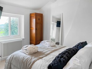 Une chambre à coucher avec un lit, une armoire, un radiateur et une fenêtre.