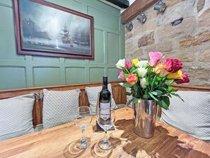 A table with a bottle of wine, two glasses, and a vase of flowers. - 2 bedroom accommodation in Whitby (Whitby)