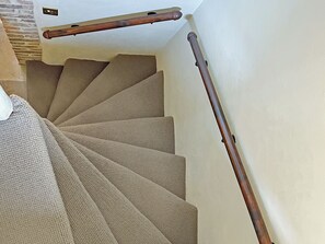 A spiral staircase with a wooden handrail and beige carpeted steps. - 2 bedroom accommodation in Whitby (Whitby)