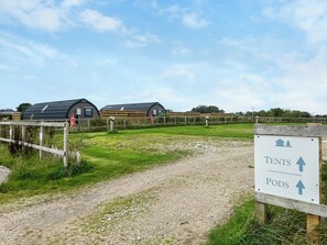 A campsite with tents and pods, a gravel path, and a wooden fence. - 1 bedroom accommodation in Blackpool (Blackpool)