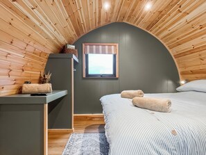 A bedroom with a sloped ceiling, a window, a bed with striped bedding, a bedside table, and a rug. - 1 bedroom accommodation in Blackpool (Blackpool)