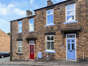 A two-story stone building with numbered doors, a red door, and a blue door. - Castle Street Cottage (Skipton)