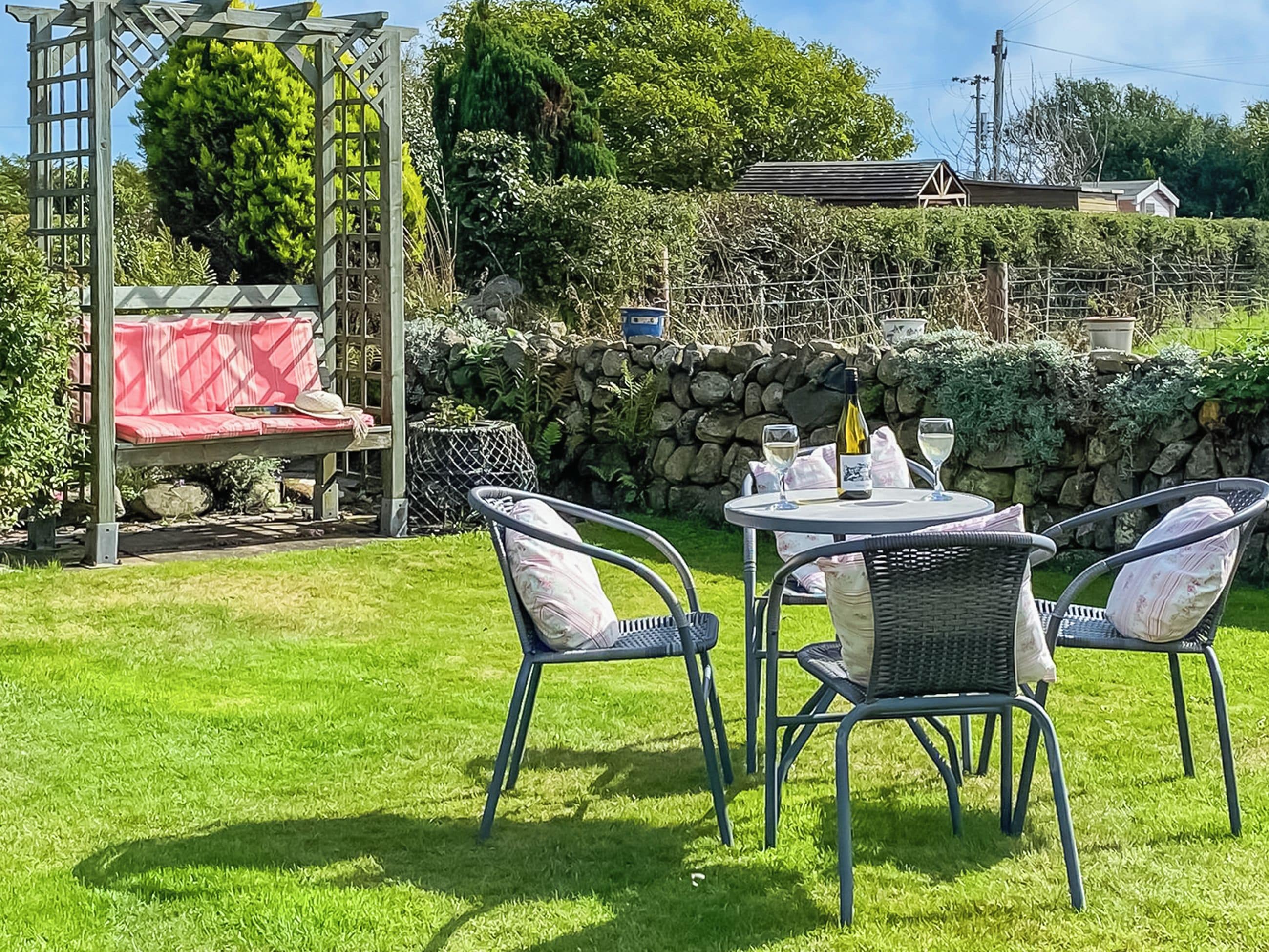 An outdoor seating area with a table and chairs, a red bench, and a pergola structure.