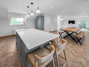 A modern kitchen with a central island, wooden chairs, a dining table, and pendant lighting. - 3 bedroom accommodation in Harthill (Harthill)