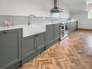 A kitchen with grey cabinets, a white countertop, a stainless steel range hood, and a herringbone-patterned wooden floor. - 3 bedroom accommodation in Harthill (Harthill)