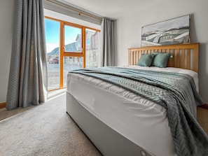 A bedroom with a large bed, a wooden headboard, a view through a glass door, and a painting on the wall. - 3 bedroom accommodation in Harthill (Harthill)