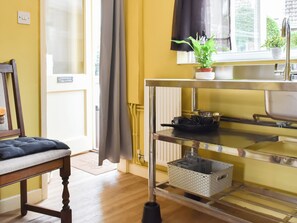 A kitchen with a window, a plant, a sink, and a chair. - We love the peaceful setting and sunny south-facing garden. (Tittleshall)