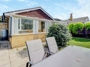 A house with a conservatory, a brick exterior, and a garden with a lawn and bushes. - 2 bedroom accommodation in Niton (Niton)