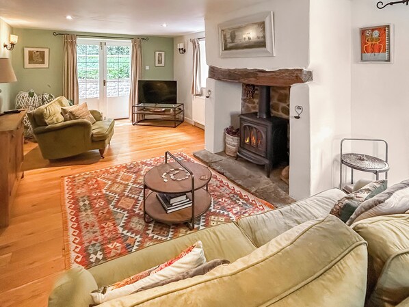 Ein Wohnzimmer mit einer Couch, einem Couchtisch, einem Fernseher, einem Kamin und einem gemusterten Teppich.