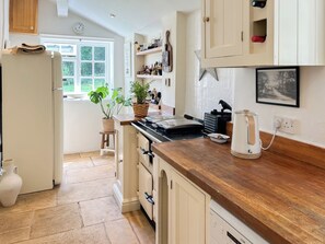 A kitchen with a wooden countertop, a stove, a kettle, and a window with a view of greenery. - 3 bedroom accommodation in Sandy Lane (Sandy Lane)
