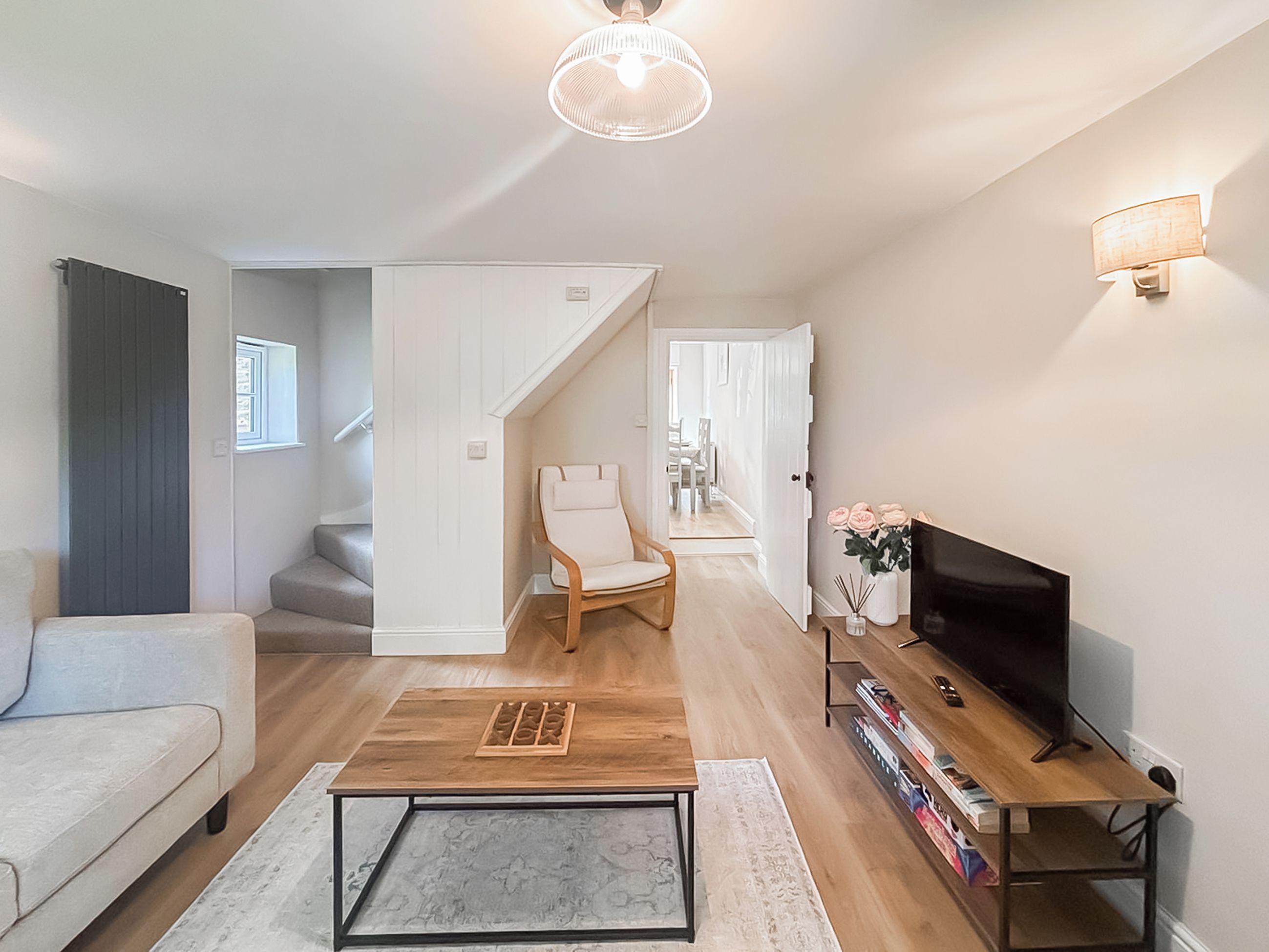 Un salon moderne comprenant un canapé, une table basse, un meuble pour la télévision et un escalier menant à une autre pièce.