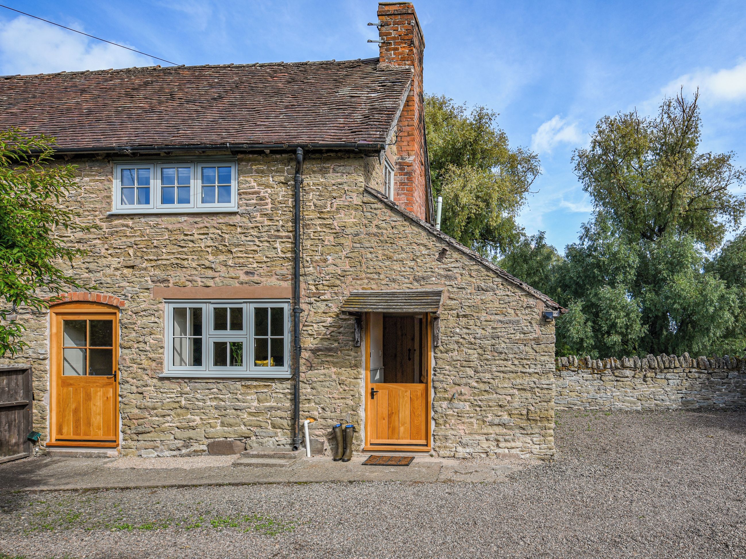 A stone house with two wooden doors, a window, and a chimney.