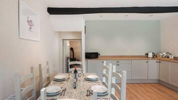Un comedor con una mesa dispuesta para cuatro, una cocina con electrodomésticos modernos y un acceso a otra habitación.