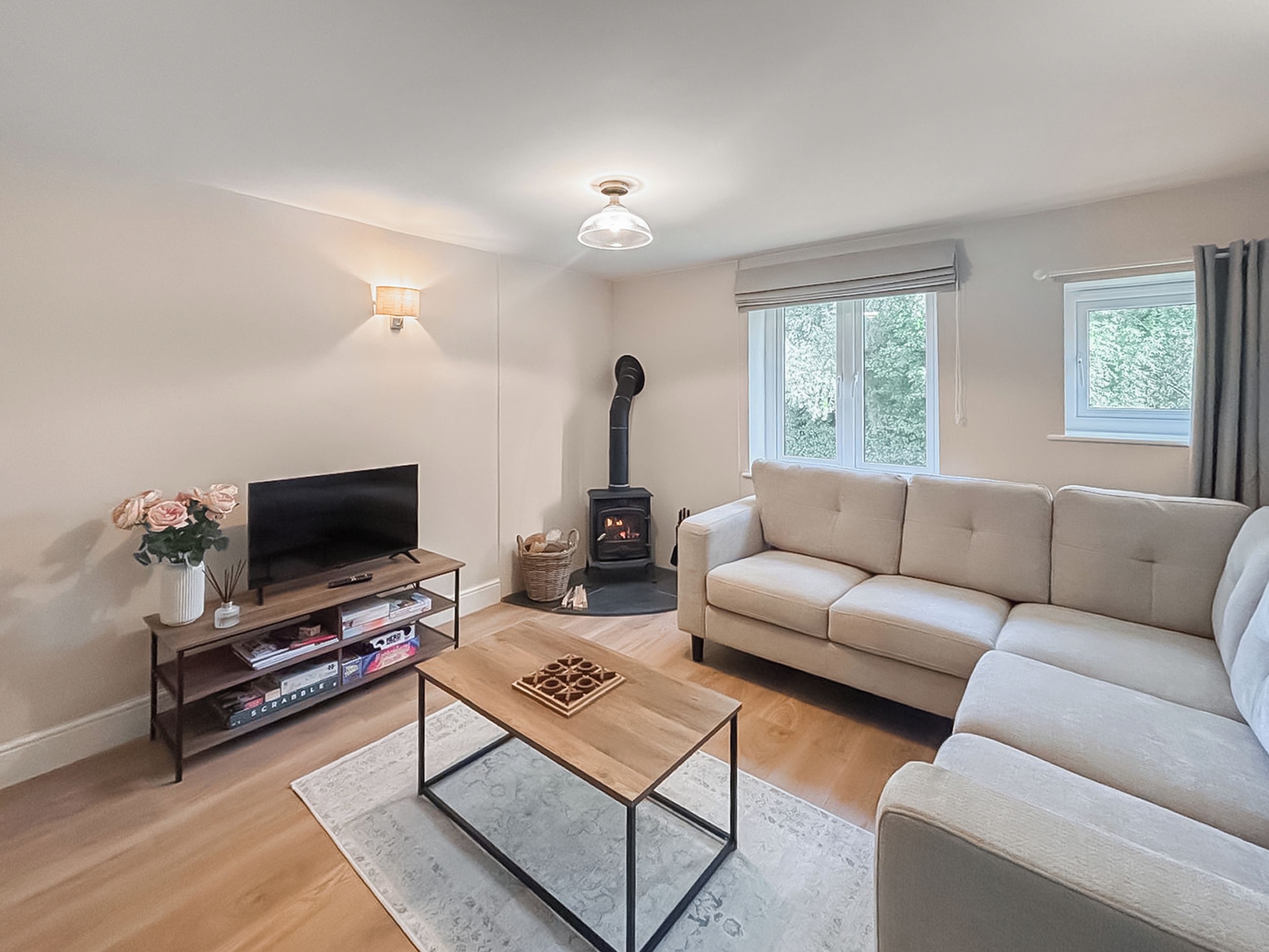 Ein Wohnzimmer mit Sofa, Fernseher, Couchtisch, Kamin und einem Fenster mit Vorhängen.