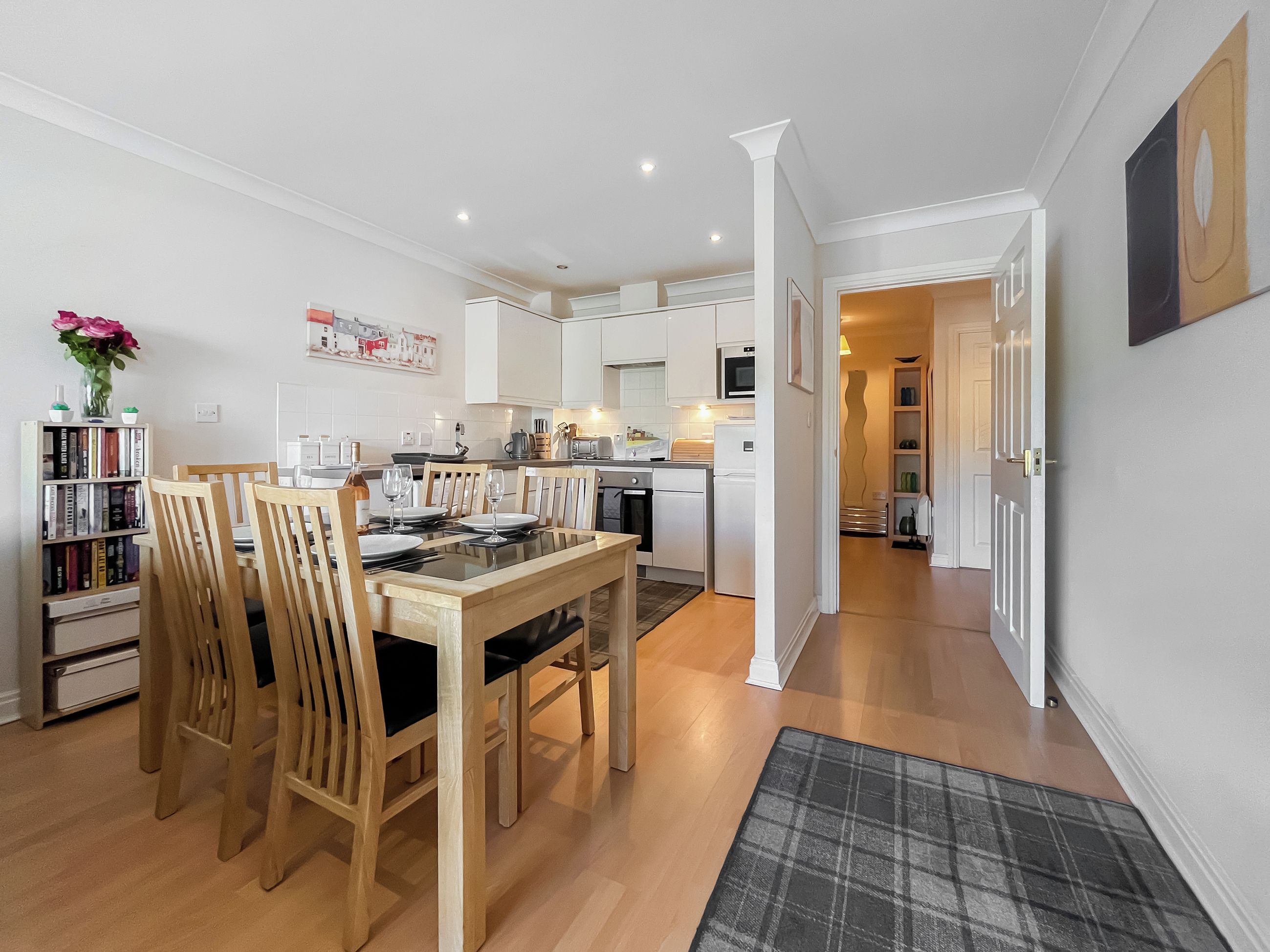 A modern kitchen with white cabinets, a dining table with chairs, and a kitchen island.