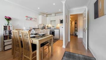 A modern kitchen with white cabinets, a dining table with chairs, and a kitchen island.