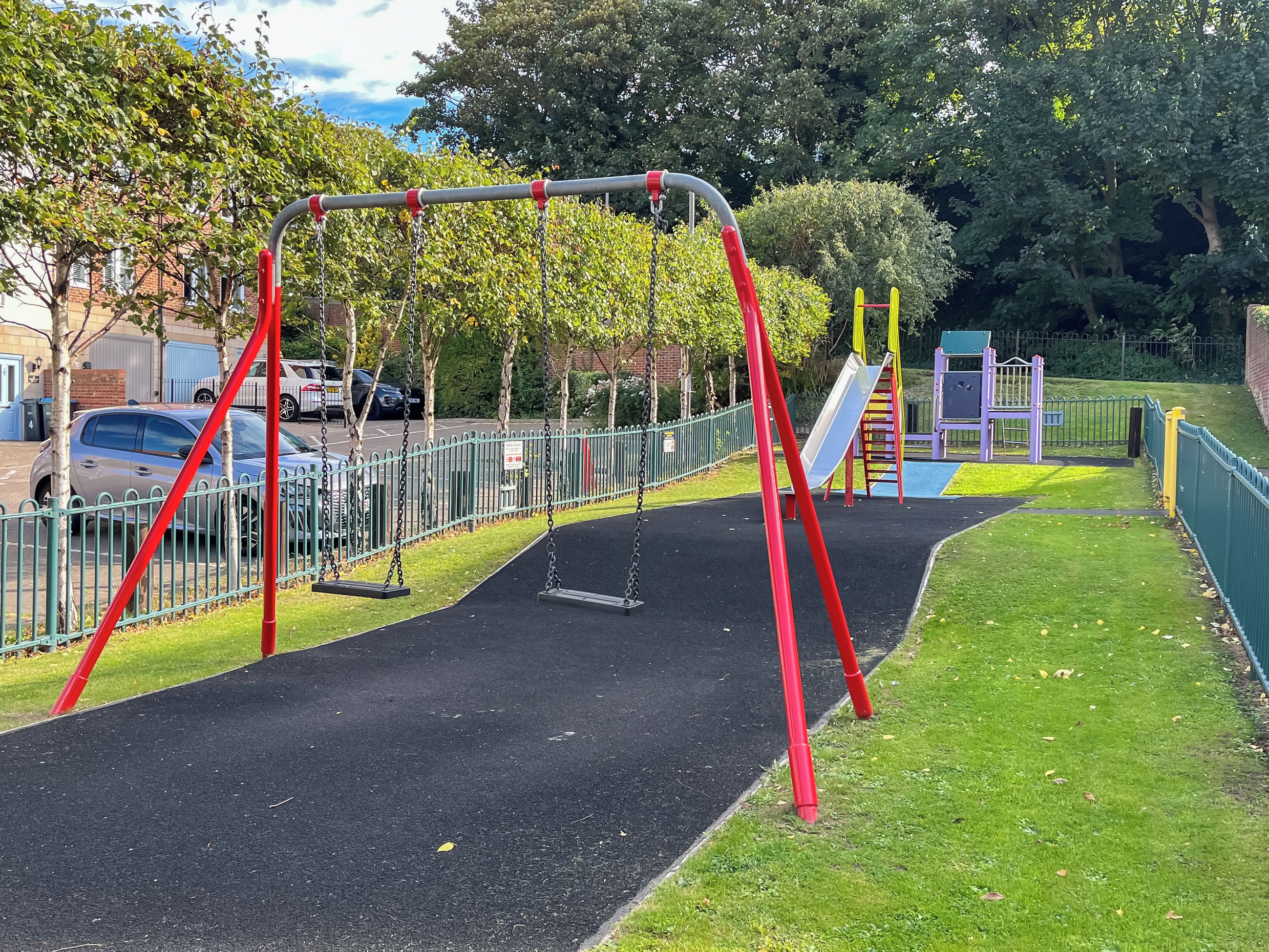 A playground with swings, a slide, and a climbing structure.