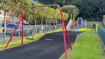 A playground with swings, a slide, and a climbing structure.