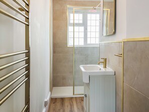 Een badkamer met een wit wastafel, een spiegel en een douchegedeelte.