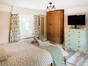 A bedroom with a bed, a wardrobe, a television, and a window with curtains. - Old Post Office Cottage (Weymouth)
