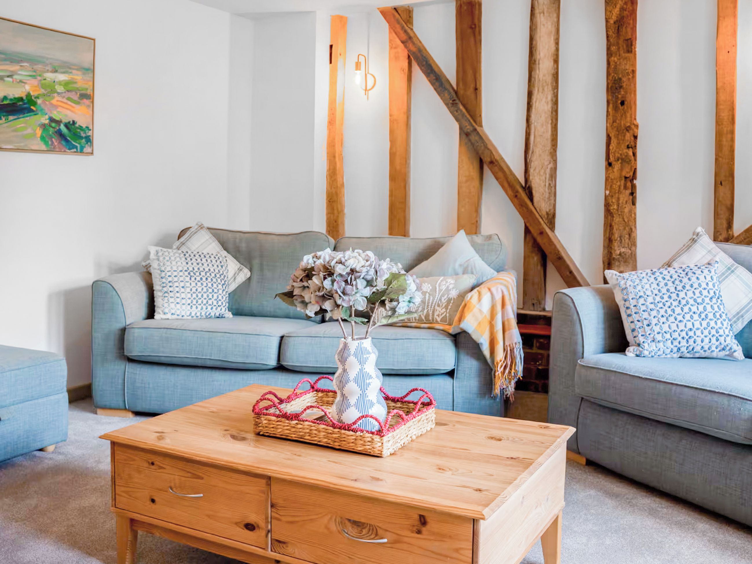 A living room with a blue sofa, a wooden coffee table, and a painting on the wall.