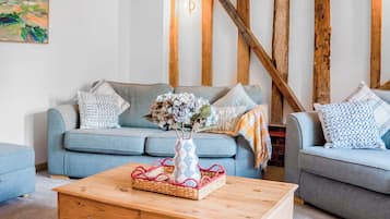 A living room with a blue sofa, a wooden coffee table, and a painting on the wall.