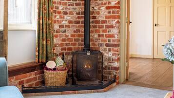 A room with a brick wall, a fireplace, a window with curtains, and a door.