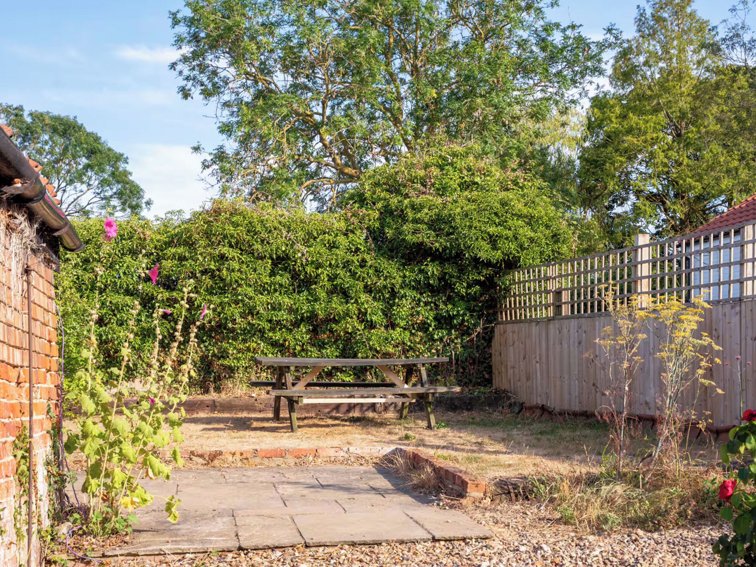 A garden area with a wooden bench, a brick wall, and a wooden fence.