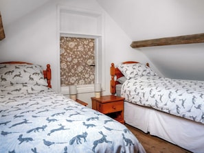 Een slaapkamer met twee bedden, een raam met bloemenbehang en een houten balk.