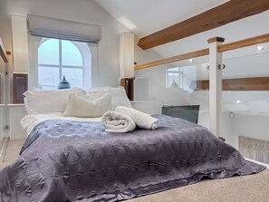 Ein modernes Schlafzimmer mit einem großen Bett, einem Fenster und einem Spiegel.