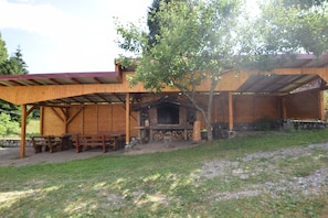 A covered outdoor area with picnic tables and a barbecue grill. - Group homes with heated pool,sauna and outdoor kitchen nestled in nature (Brod Moravice)