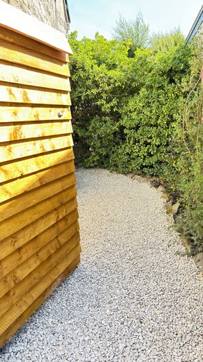 A wooden building with a gravel path leading to a green hedge. - Charming, renovated Penty, 250 meters from the sea, the Eckmühl Lighthouse, and Pointe de la Torche (Penmarch)