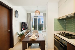 Eine moderne Küche mit Essbereich, einem an der Wand befestigten Fernseher und Blick auf die Stadt durch das Fenster.