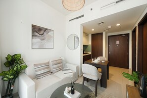 A modern living room with a sofa, a dining table, and a kitchen area. - Bloomfields 1BR in Reva Residences (Dubai)