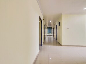 A long, narrow hallway with doors on both sides, leading to a room with a patterned curtain. - Hotel O SS ELITE (Hyderabad)