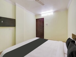 A bedroom with a bed, a ceiling fan, a door, and a wall-mounted light fixture. - Hotel O SS ELITE (Hyderabad)