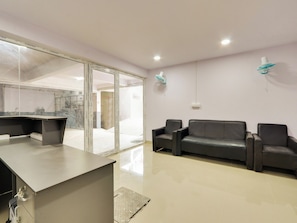 A modern office space with a reception desk, two leather sofas, and a glass partition. - Hotel O SS ELITE (Hyderabad)