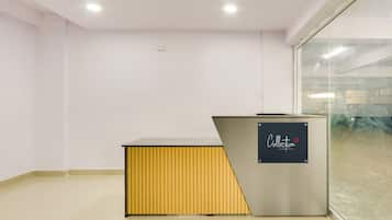 Un área de recepción con mostrador, separador de vidrio y piso de baldosas.