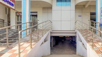 Entrada de um edifício com uma placa indicando 'ELITE ROOMS' e uma escadaria que leva a um andar superior.