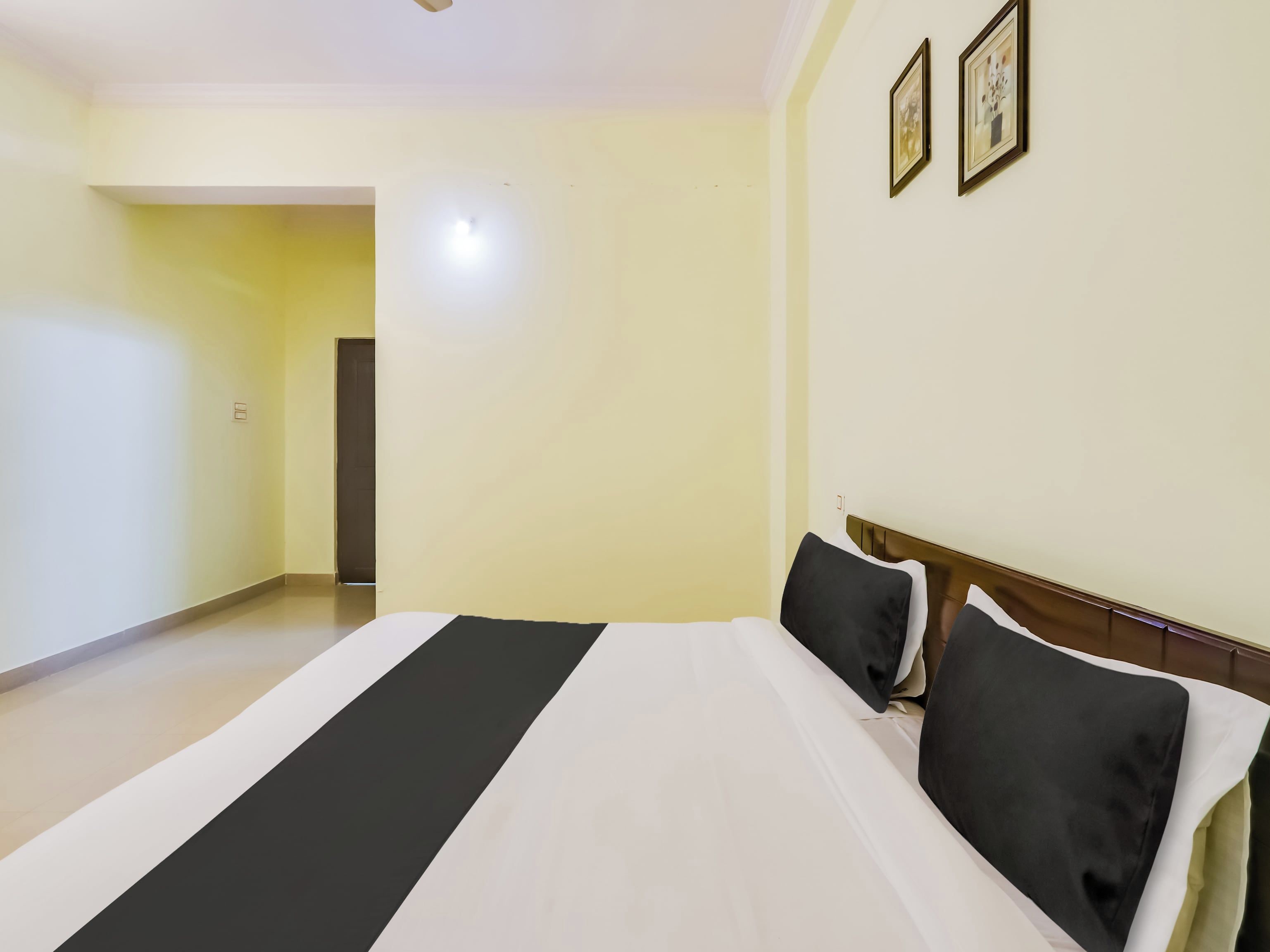Quarto de hotel com cama, porta e luminária.