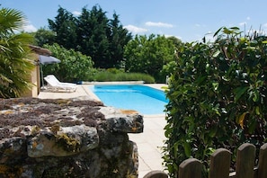 A swimming pool with a stone wall and a wooden fence in the foreground. - Le pied a terre - 6 or 8 people (MONTFERRAND DU PERIGORD)