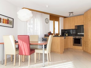 Eine moderne Küche mit Holzausstattung, einem eingebauten Backofen und einem Essbereich mit Tisch und Stühlen.