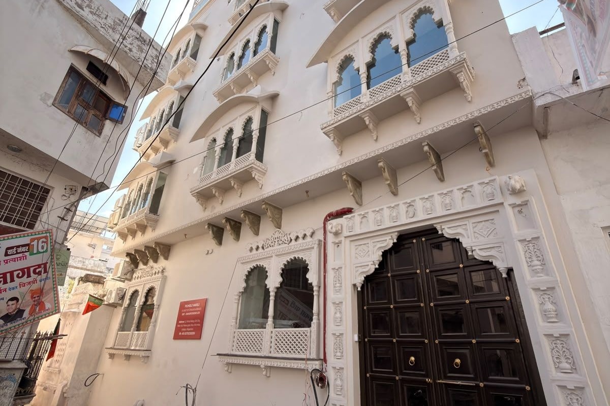 A multi-story building with ornate white balconies and a large dark wooden door.