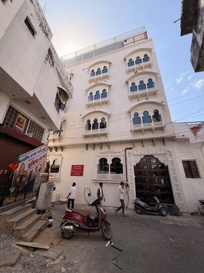 Un edificio a più piani con elementi architettonici tradizionali, un cancello e uno scooter parcheggiato.