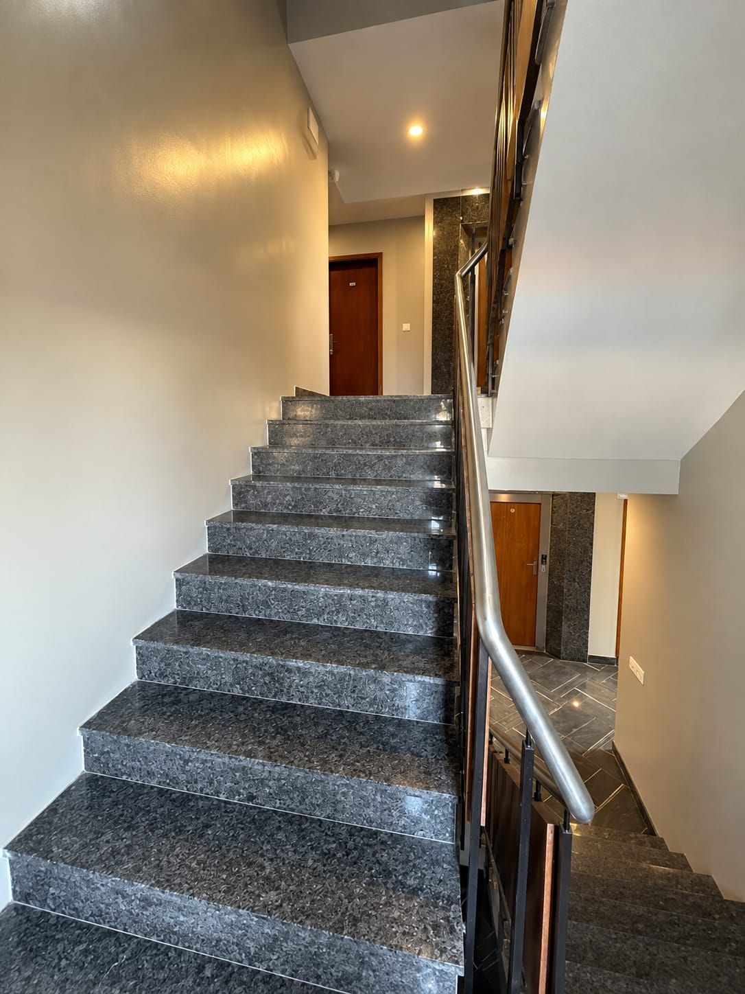 Un escalier avec une rampe métallique menant à un palier.