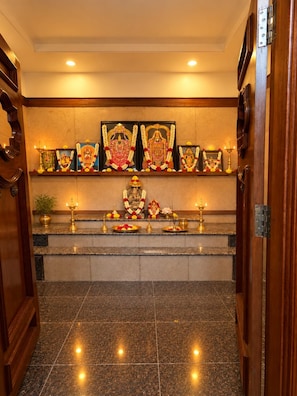 A corridor with a shrine at the end, featuring religious idols and offerings. - Hotel Grand Mirage  (Chennai)
