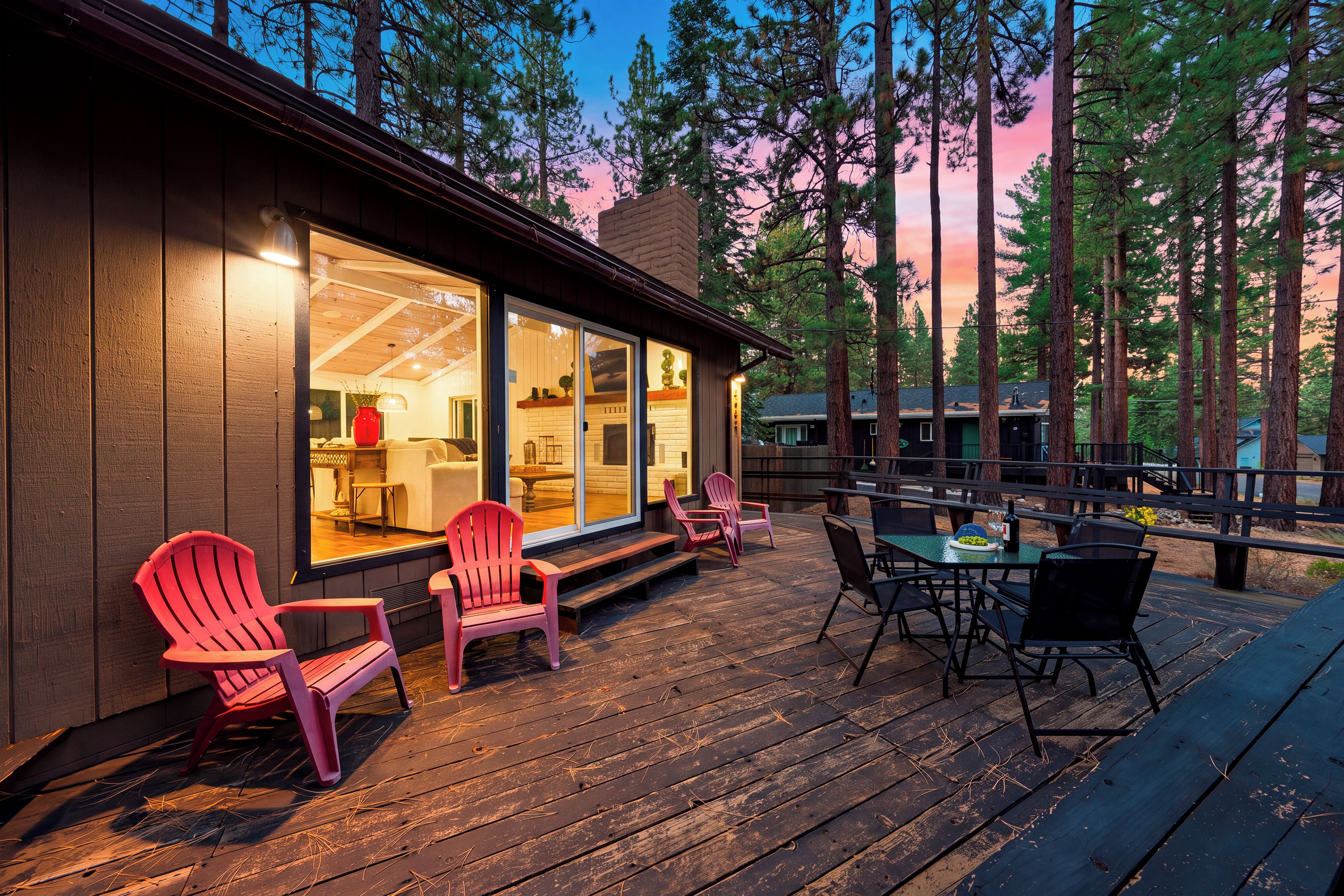A wooden deck with outdoor seating, overlooking a forested area.