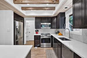 A modern kitchen with dark cabinetry, stainless steel appliances, and a herringbone tile backsplash. - South Lake Tahoe • Fireplace + Pine-View Deck + Trail Access | Timberlight (South Lake Tahoe)